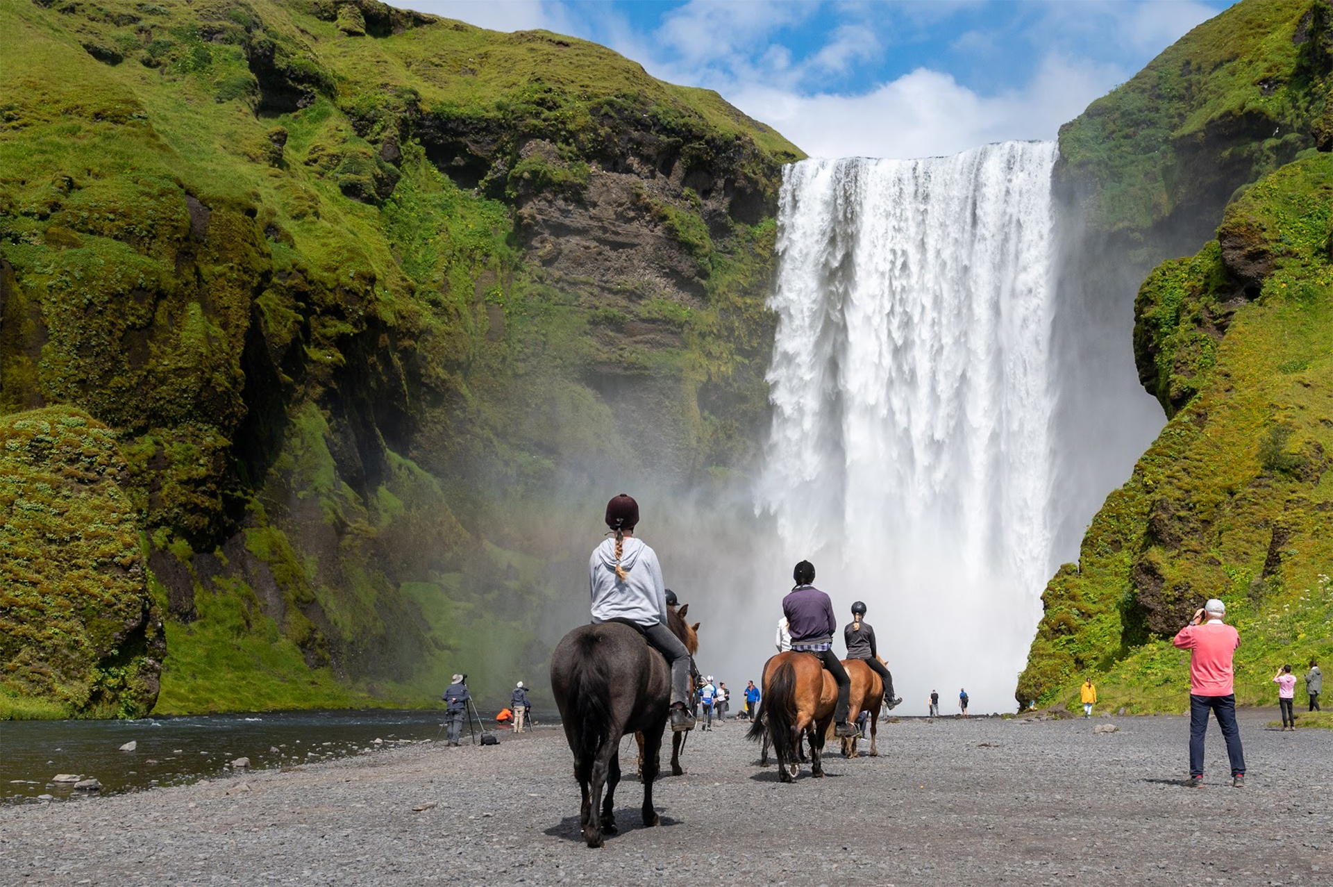 Travelers ride horseback toward Skogafoss Icelandic horses